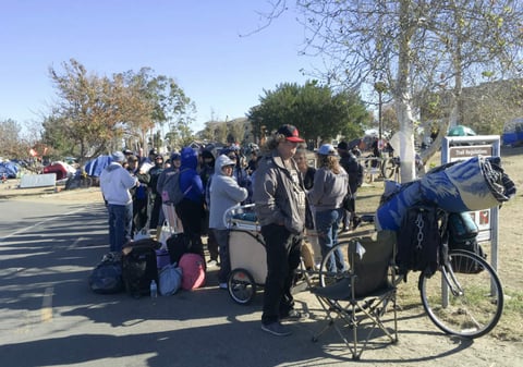 Homeless people line up in preparation to move from their homeless encampment along a riverbed in Anaheim, Calif. on Tuesday, Feb. 20, 2018. 